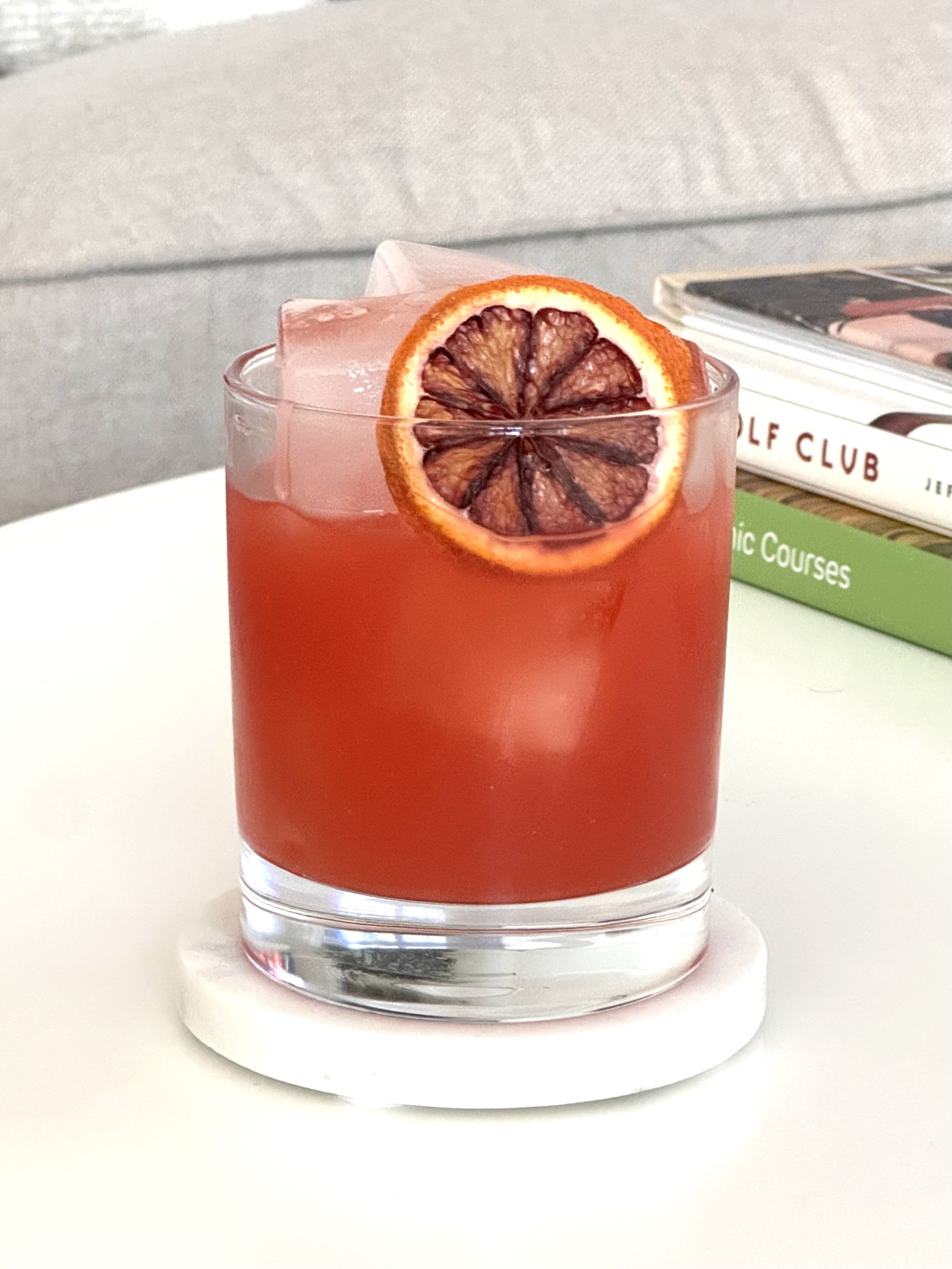 Red drink in a double old fashioned glass with a dried orange wheel