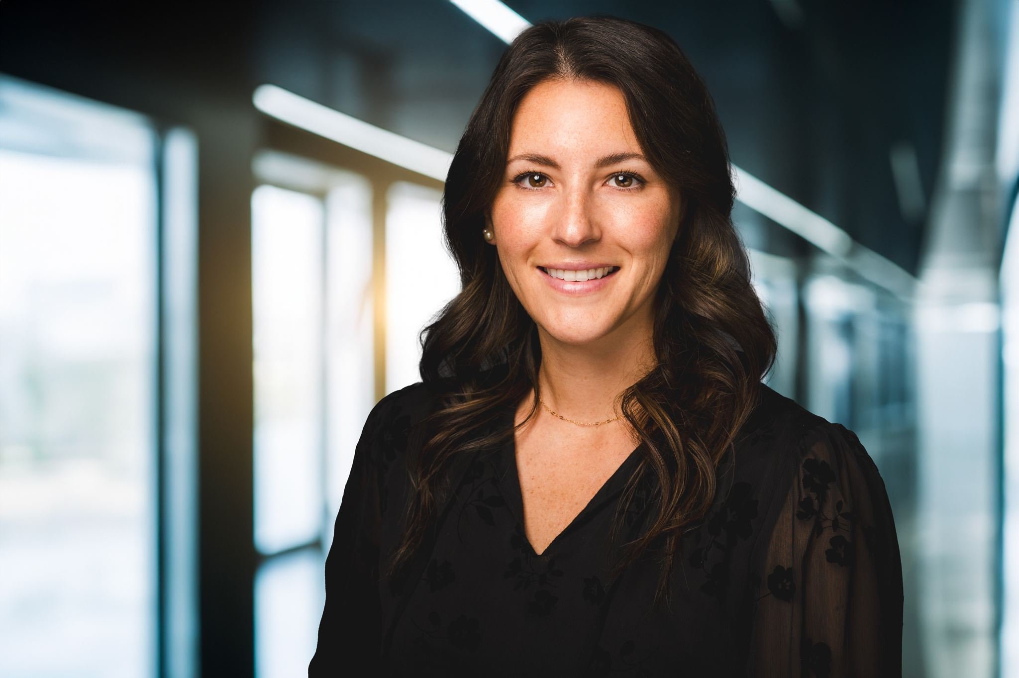 Professional corporate headshot of a businesswoman in a black blazer against a light gray background, photographed by Washington, D.C. headshot photographer Gabriele Stonyte