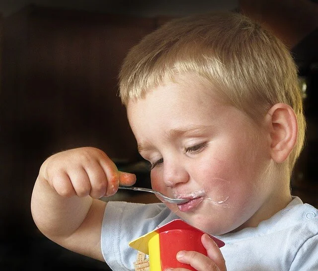 Boy eating yoghurt with spoon.jpg