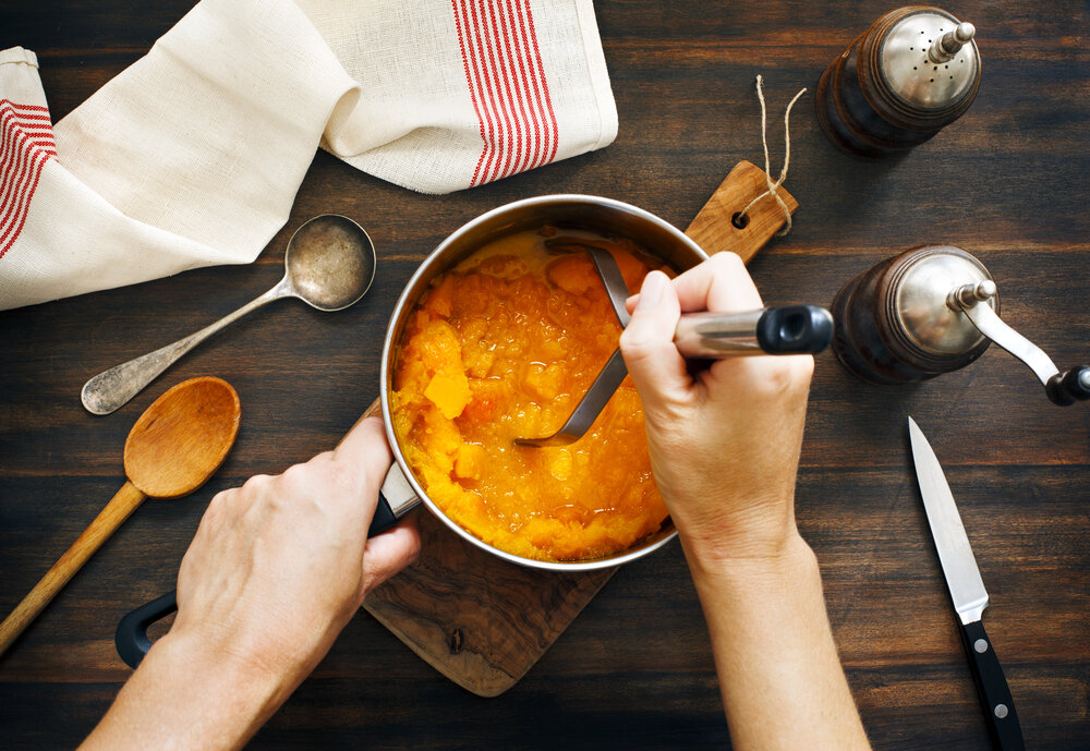 pumpkin being mashed in a saucepan