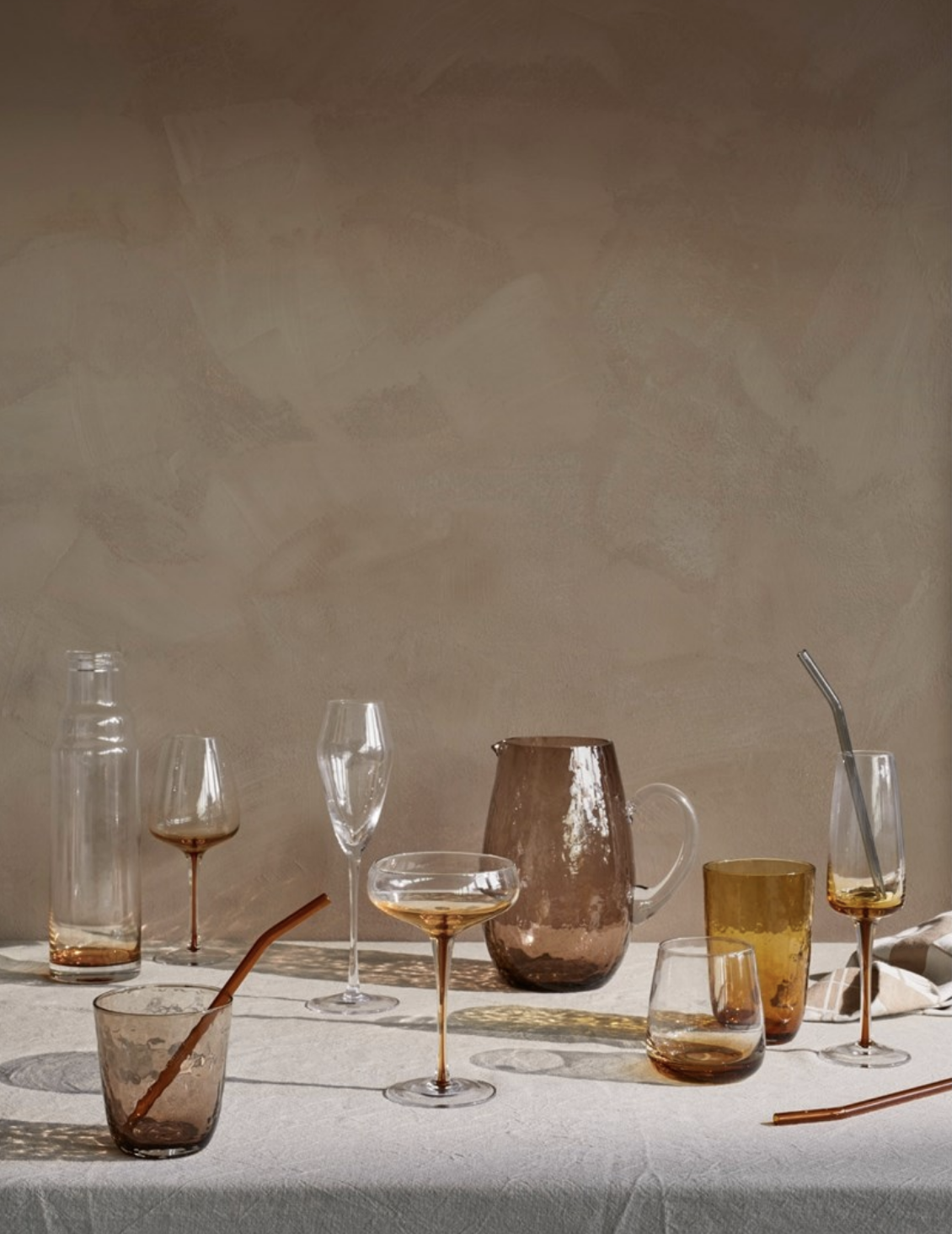   White Wine Glass Amber  , Champagne Glass Amber ,  Cocktail Glass Amber ,  Tumbler Glass Amber ,  Carafe with Lid Amber,    Jug Hammered,   Tumbler Hammered , and  Champagne Glass Sandvig  all created by  Broste Copenhagen.   