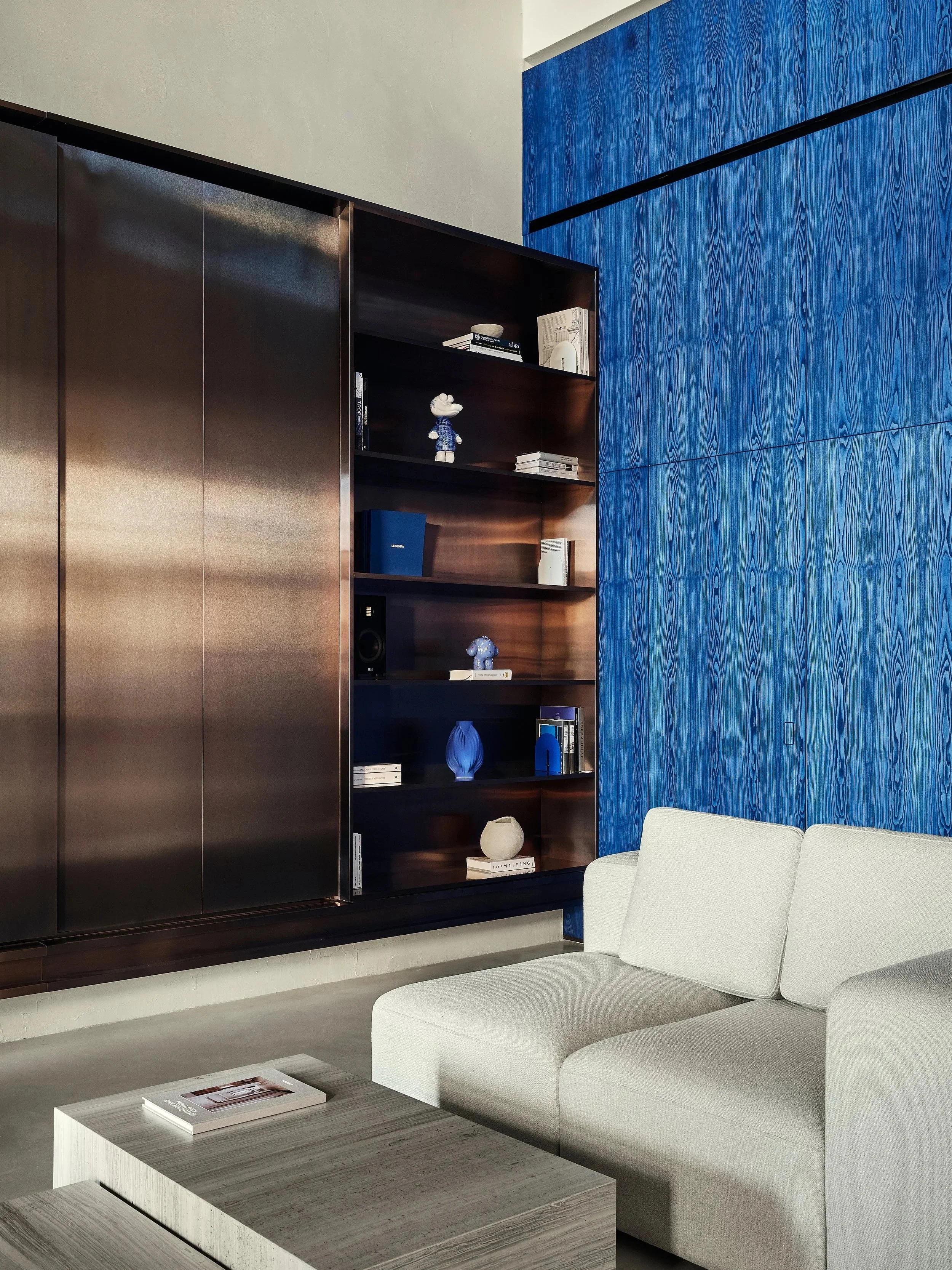 legenda-sales-office-blue-veneer-wall-copper-bookshelf-white-sofa