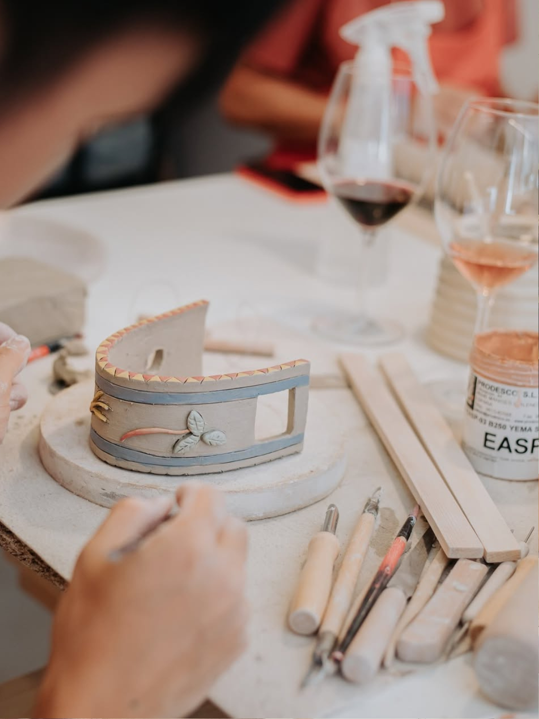 A participant shaping a clay piece during a hand-building ceramic workshop at Úrsula Cerâmica's light-filled studio in Lapa, Lisbon, guided by ceramist Úrsula.