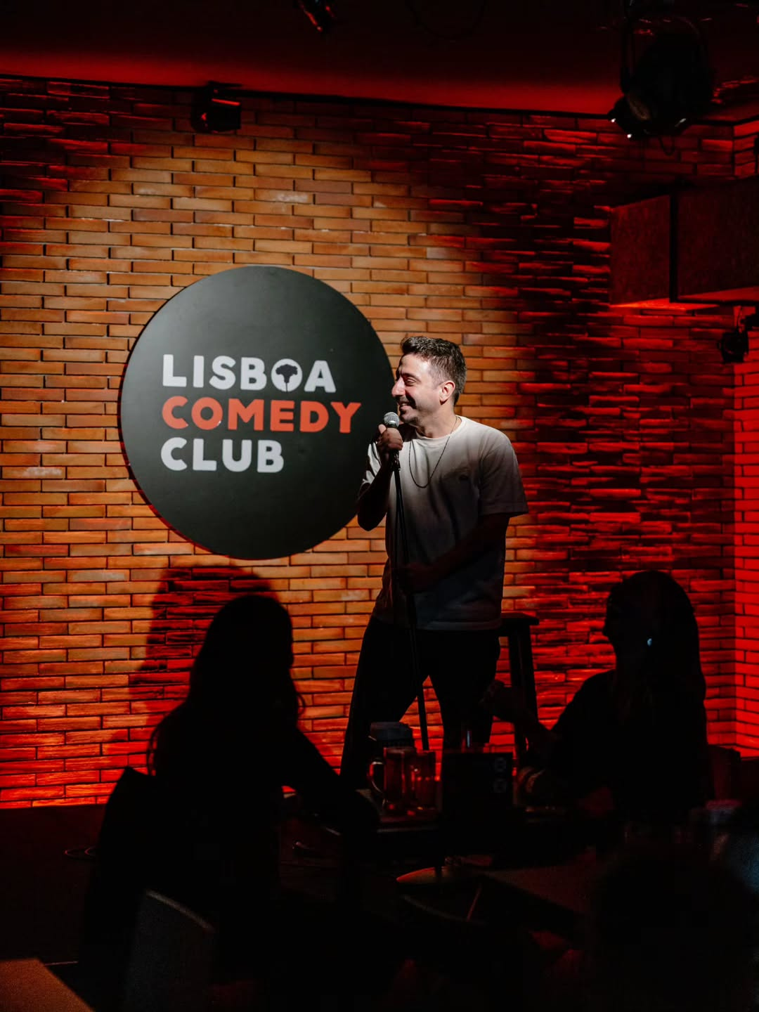 A stand-up comedy performance at Lisboa Comedy Club on Av. Duque de Loulé in Lisbon, hosting English-language comedy nights every Sunday in June.
