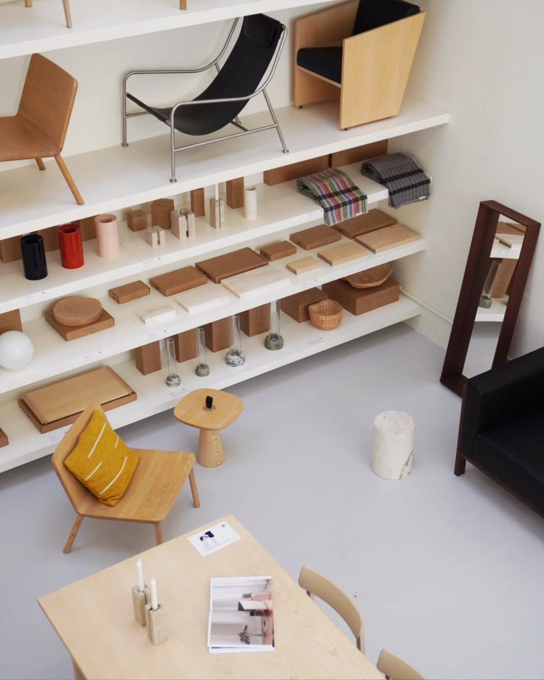 Overhead view of a curated design showroom with wooden furniture, ceramic objects and homeware on white shelves at Lisbon Design Week