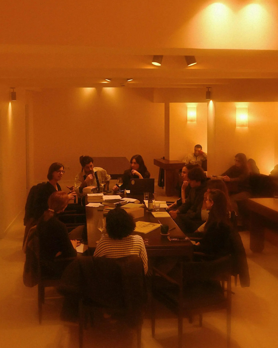 Small group gathered around a table for a guided journaling workshop at Good Company bookstore, Lisbon, bathed in warm amber light