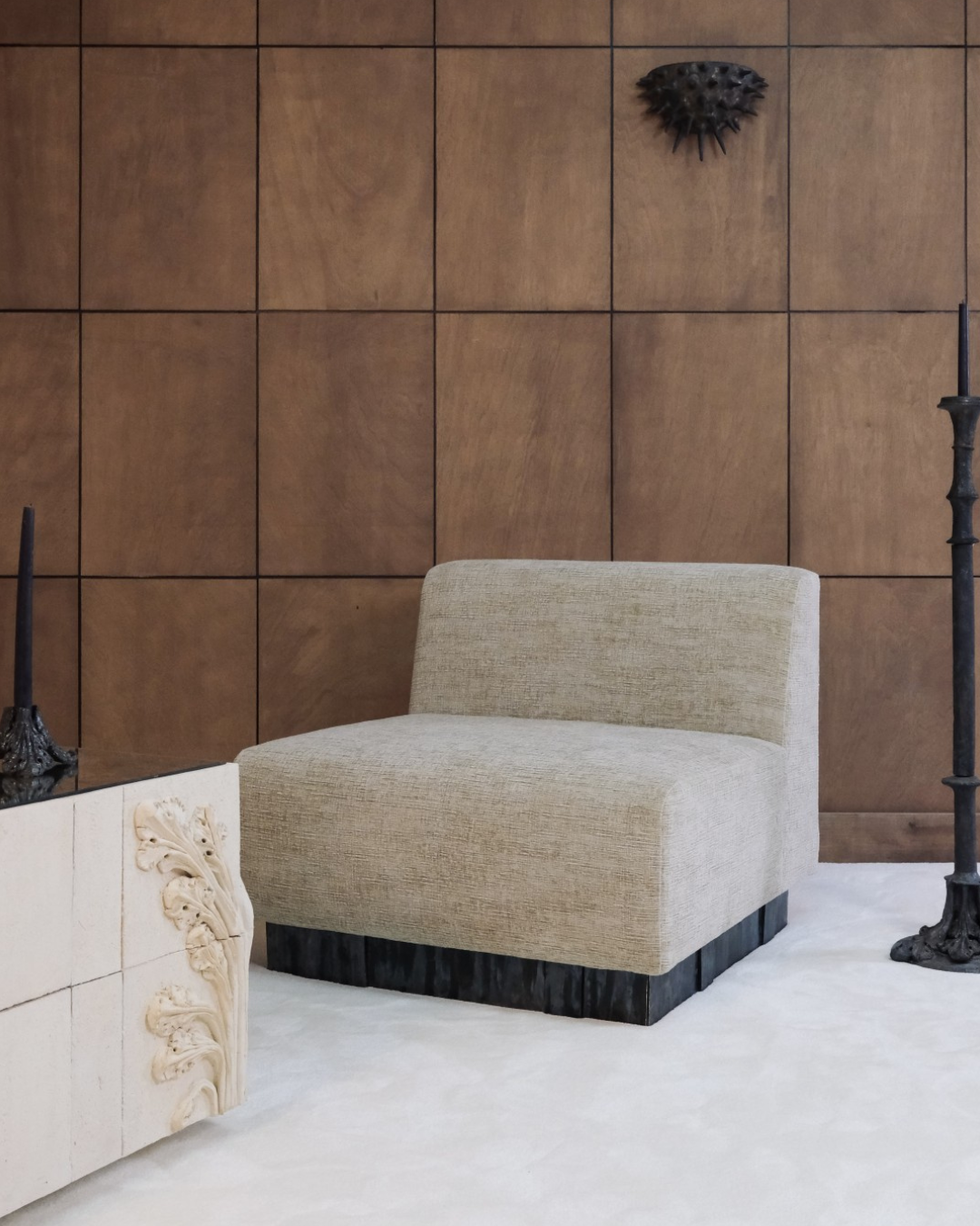 Textured linen armchair against a panelled wood wall with ornate candlesticks and carved stonework at Lisbon by Design