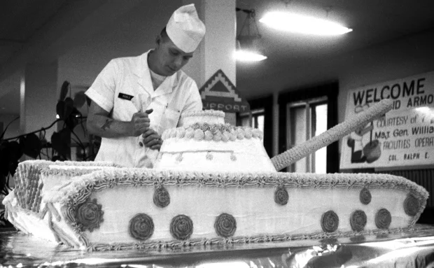 Frankfurt, West Germany, October, 1963: Sgt. 1st Class Dawson Riddle of B Co., 14th Quartermaster Battalion, puts the finishing touches on a tank-shaped cake — weighing over 200 pounds — baked to welcome the first Operation Big Lift arrivals to Rhein-Main Air Base. In Big Lift, described as "a historic demonstration of the United States' power to throw a quick fighting punch overseas," more than 200 air transports were bringing 16,000 2nd Armored Div. soldiers and supporting units to Germany for war games. Stars & Stripes photo