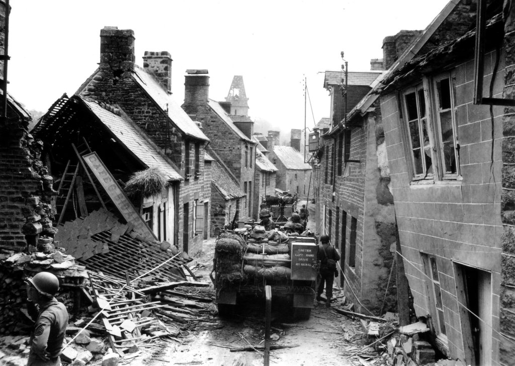 Half-tracks of Combat Command A move slowly down rue Saint Michel.