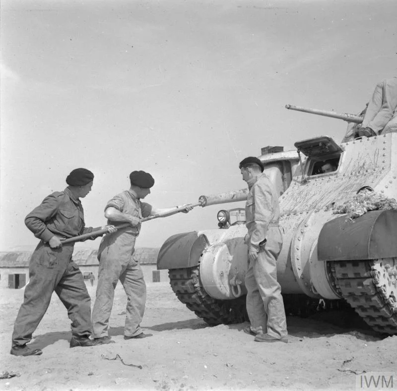 The crew of a 3rd Royal Tank Regiment Grant tank clean the vehicle's sponson-mounted 75mm gun, 20 Feb 1942. IWM photo E 8580