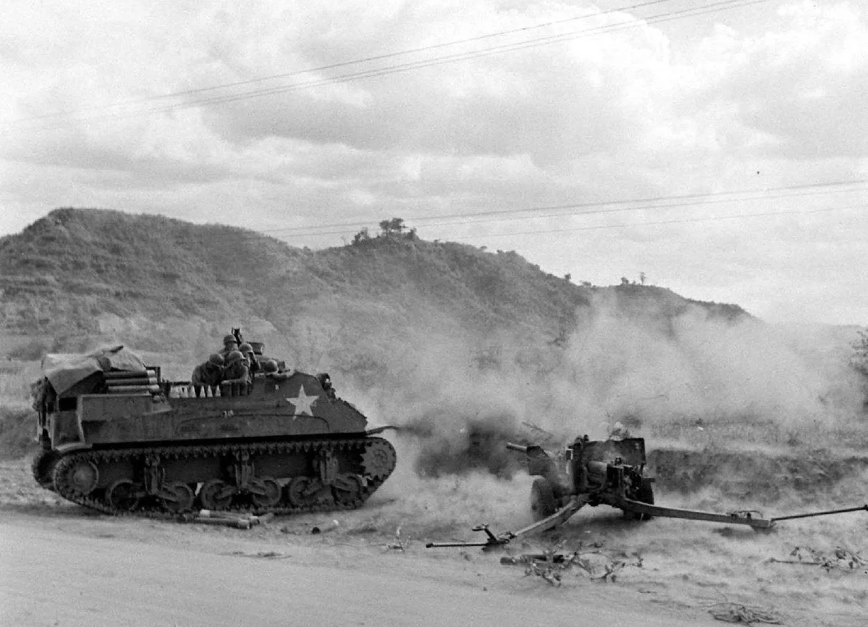 M7 Priest (Early Production) in full recoil. 57mm M1 anti-tank gun nearby.