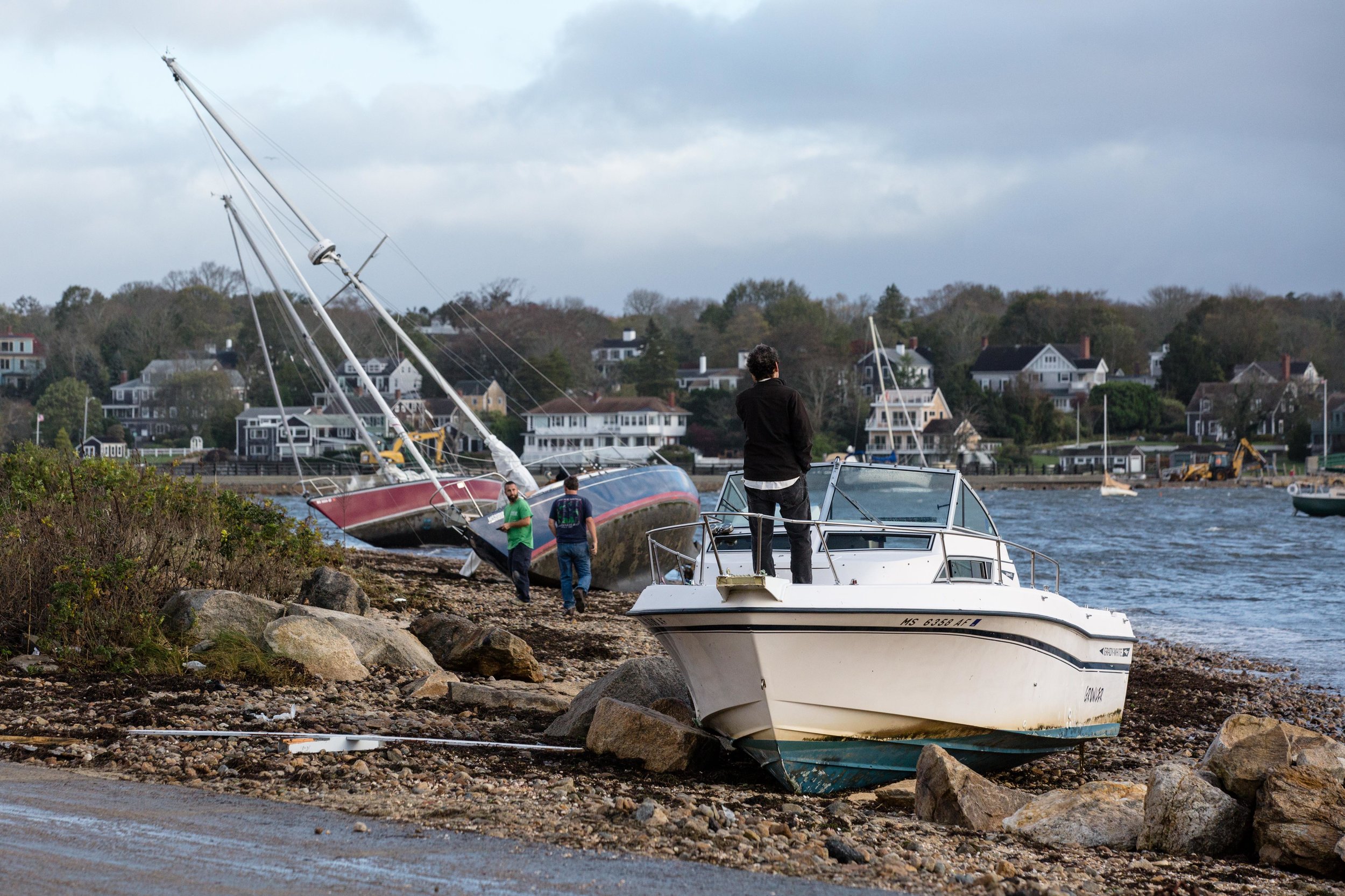  A man stands on the bow of his beached powerboat. 