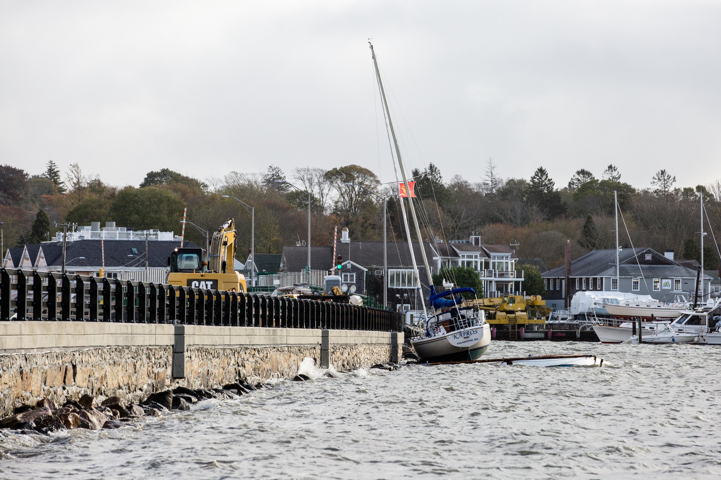  A sailboat gets stuck against the causeway while a capsized powerboat lies beneath it. 