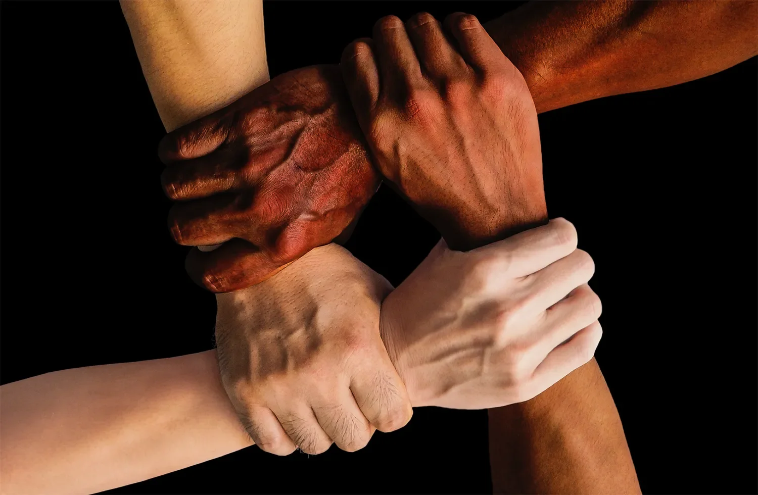 Multiple hands of different skin tones are joined together in a display of unity and support.