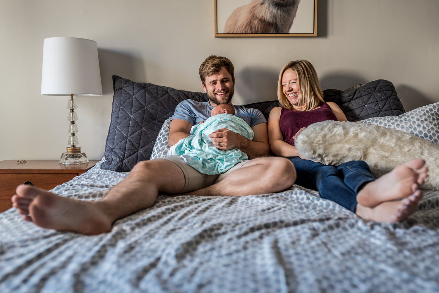 joyful-mama-and-daddy-with-brand-new-baby-boy-in-bedroom