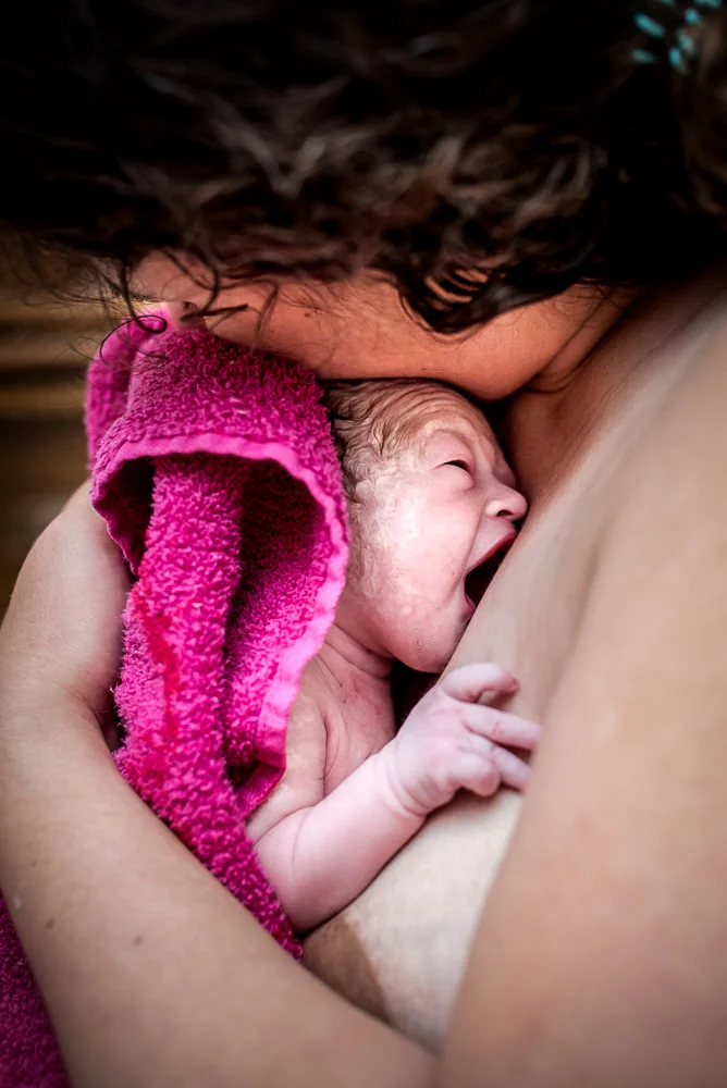 brand new baby held tight in mom's arms.jpg
