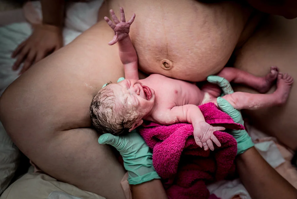 moment of birth midwife hands baby to mom.jpg
