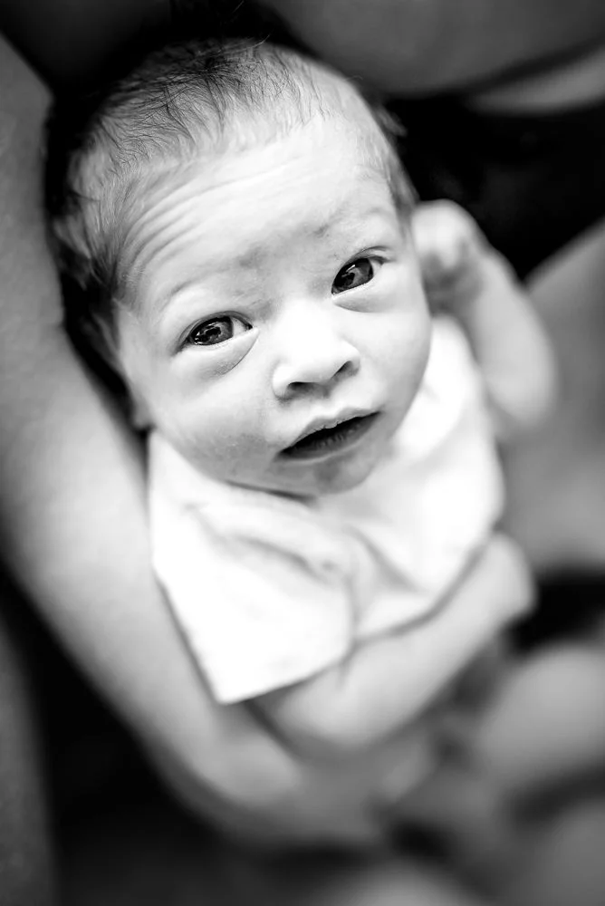 newborn documentary photographer takes photo of baby looking straight into camera.jpg