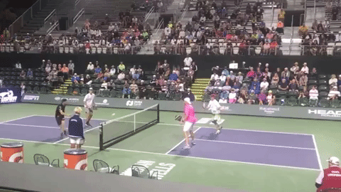 With Yates pulled wide, Wright (pink shirt) must be weary of a potential around-the-post drive. Instead, Yates plays a well-disguised topspin lob. Because he is off the court, he has a good angle to play a lob over Wright’s backhand side (avoiding the dangerous forehand smash). Wright appears surprised at the lob and hesitates. Instead of hitting it out of the air, he lets it bounce. He is now in an extremely defensive position and can’t make the drop.