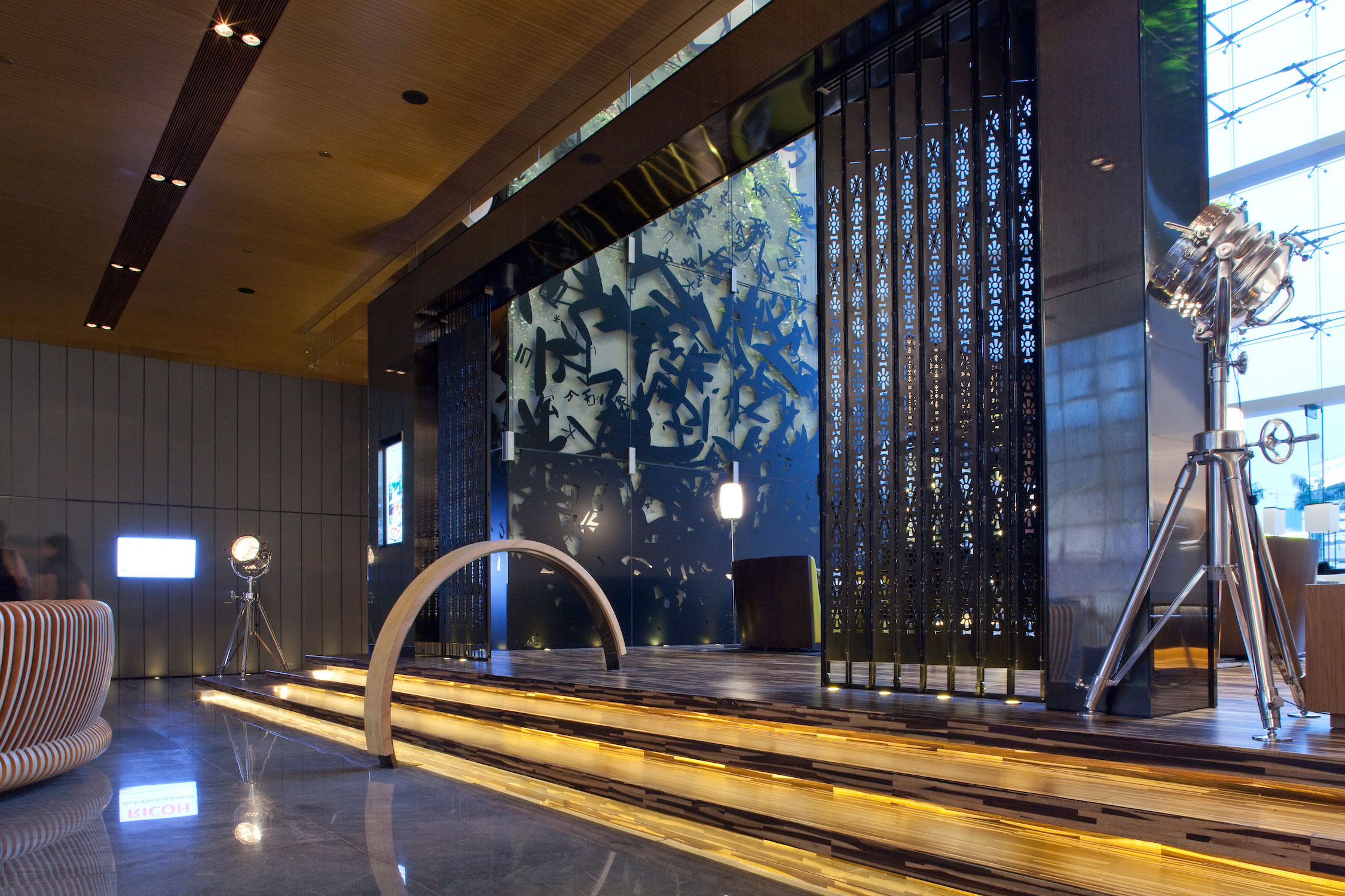 The entrance portal and oversized back bar counter to the lobby bar, is created using the fast disappearing, but ubiquitous, Hong Kong element of sliding folding steel gates with punched hole patterns and evoke fond memories in many local patrons. The glass lift tower displays the graphic work of a local artist incorporating Chinese character forms.
