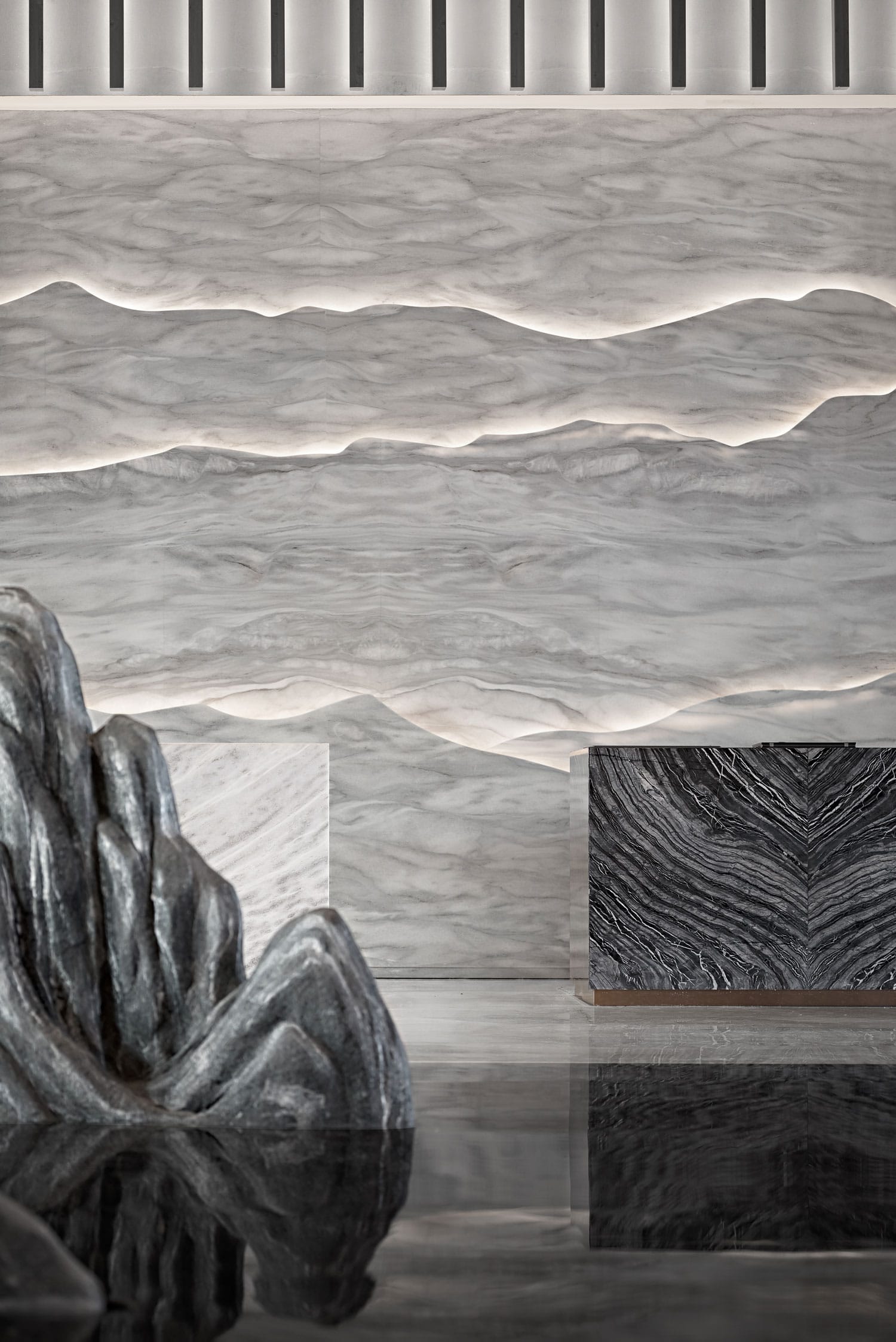 The hotel design is inspired by the mountain landscape and the Great Wall in Badaling. Using layers and overlapping big slabs of natural stone with lighting effect to create the endless mountain silhouette as a back drop for the reception.