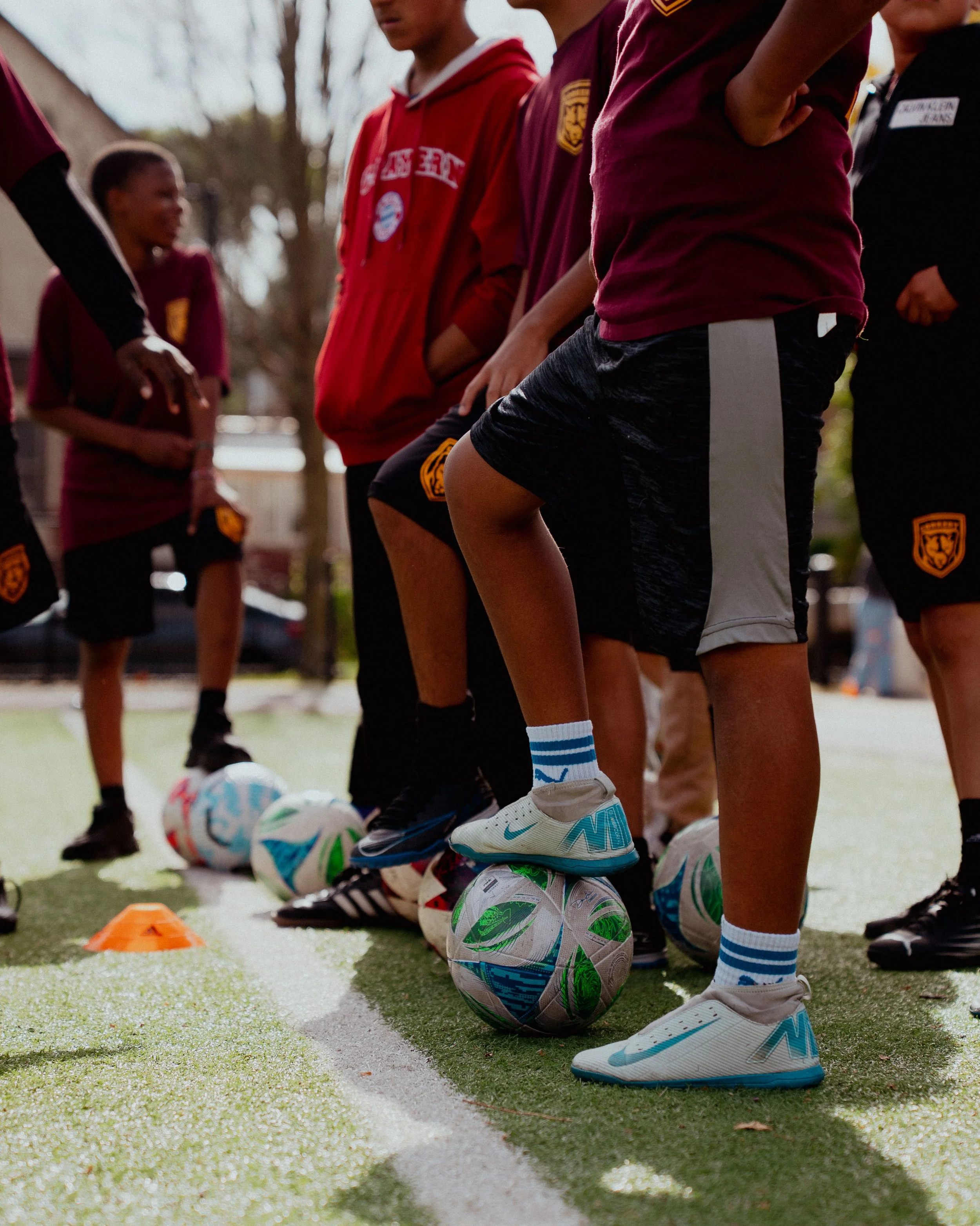 Children in sportswear practicing soccer on a field, each with a soccer ball at their feet, during a training session.