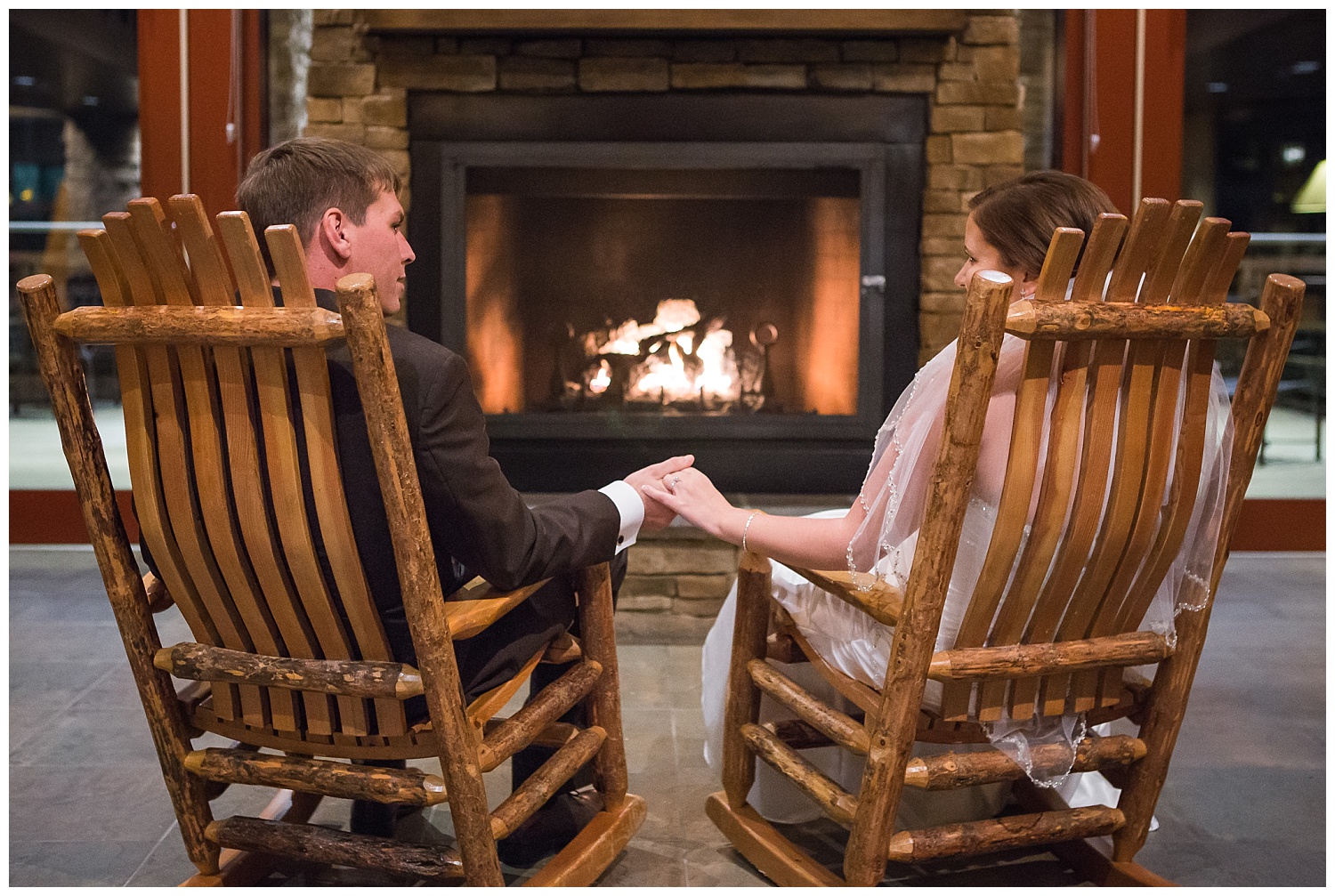 bride and groom sit on rocking chairs by fireplace