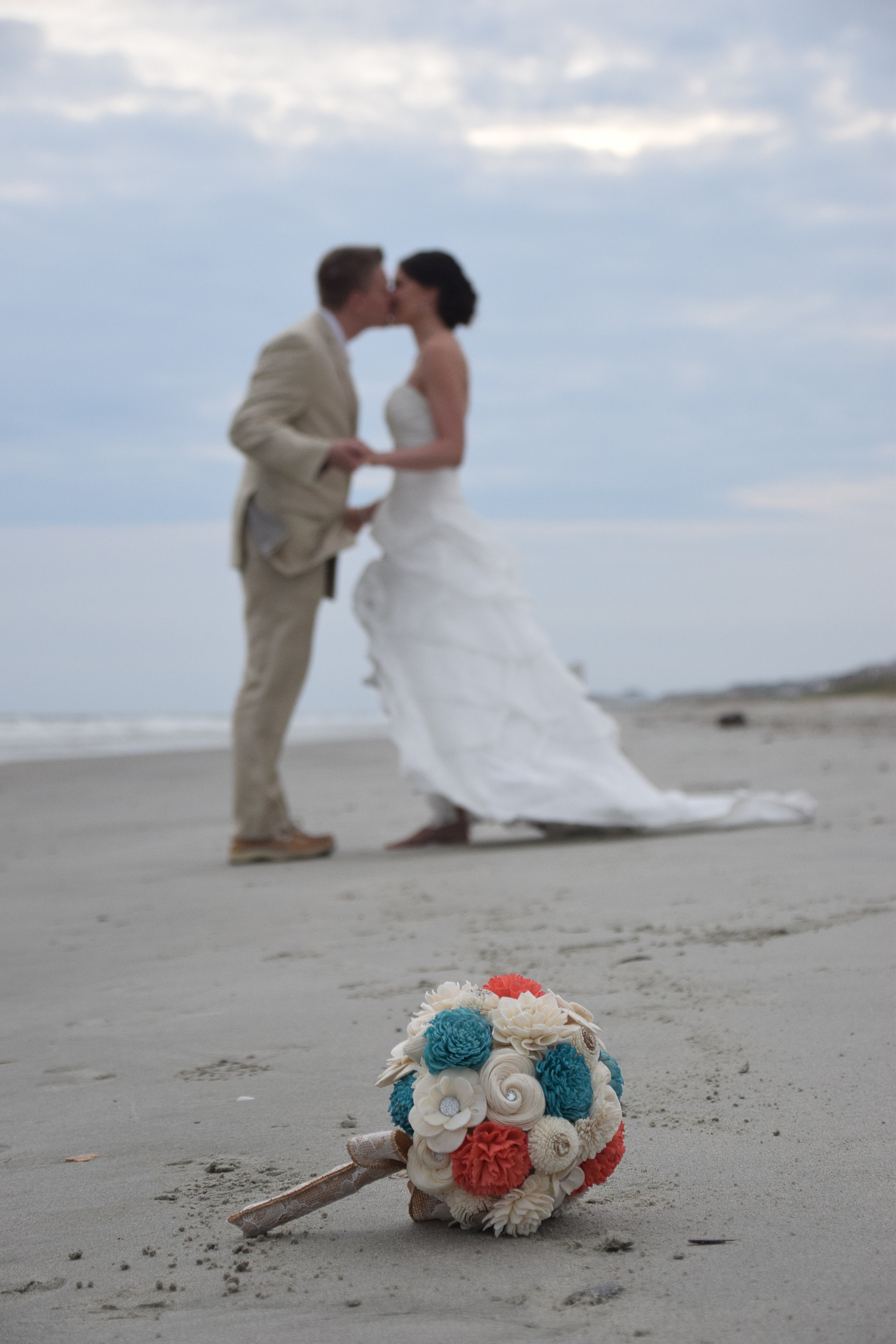 Bride and groom kissing on the beach.