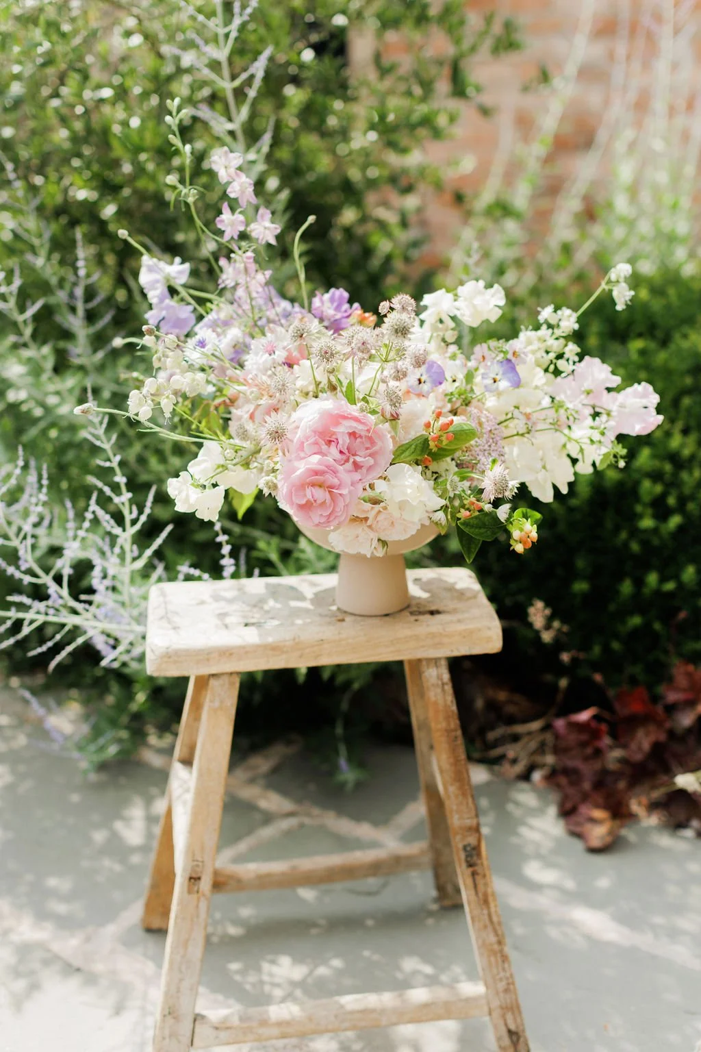 light pink peonies in a vase on a stool