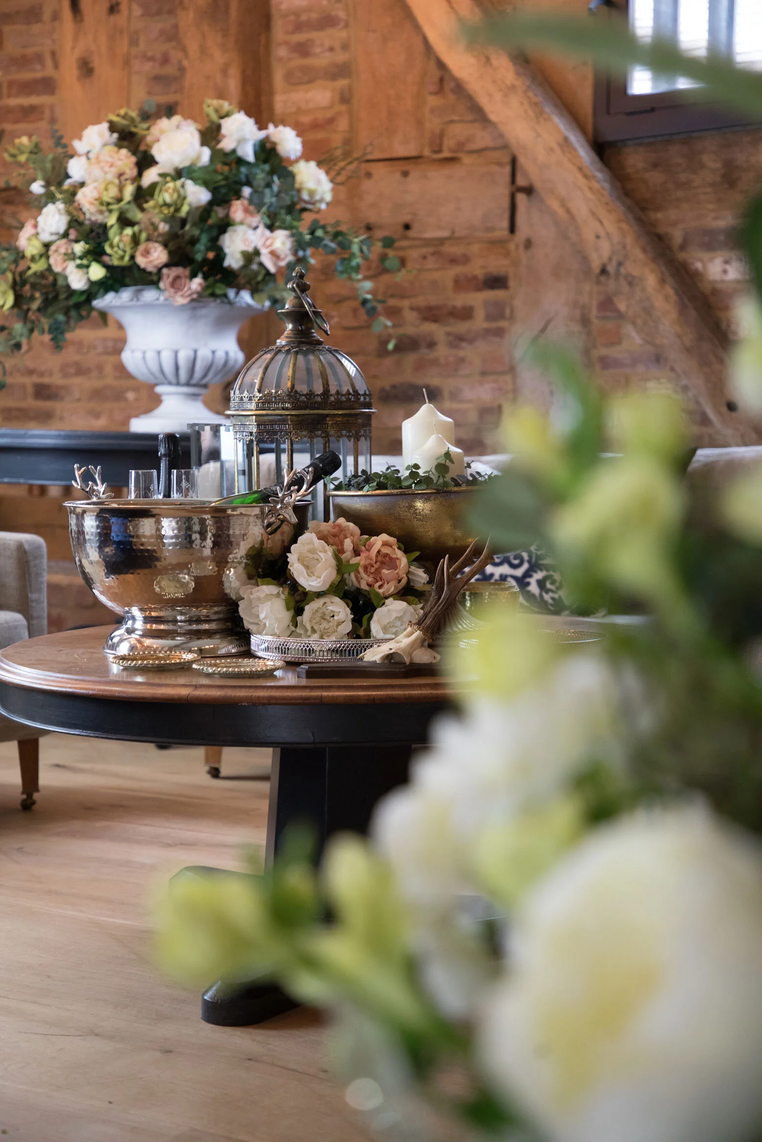Champagne bottle and flute glassed arranged in a large silver freestanding cooler, surround by floral arrangements