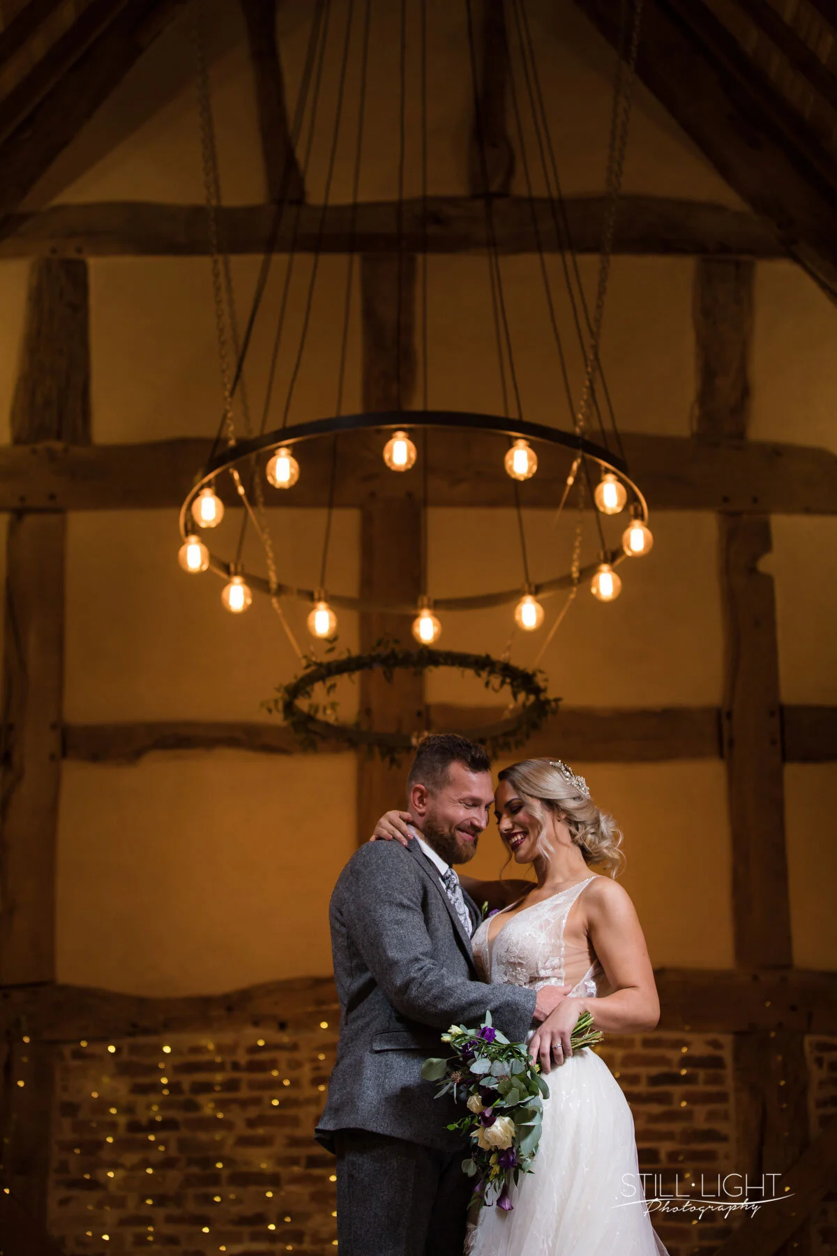 Bride and groom sharing a romantic moment beneath the oak beams of the historic barn