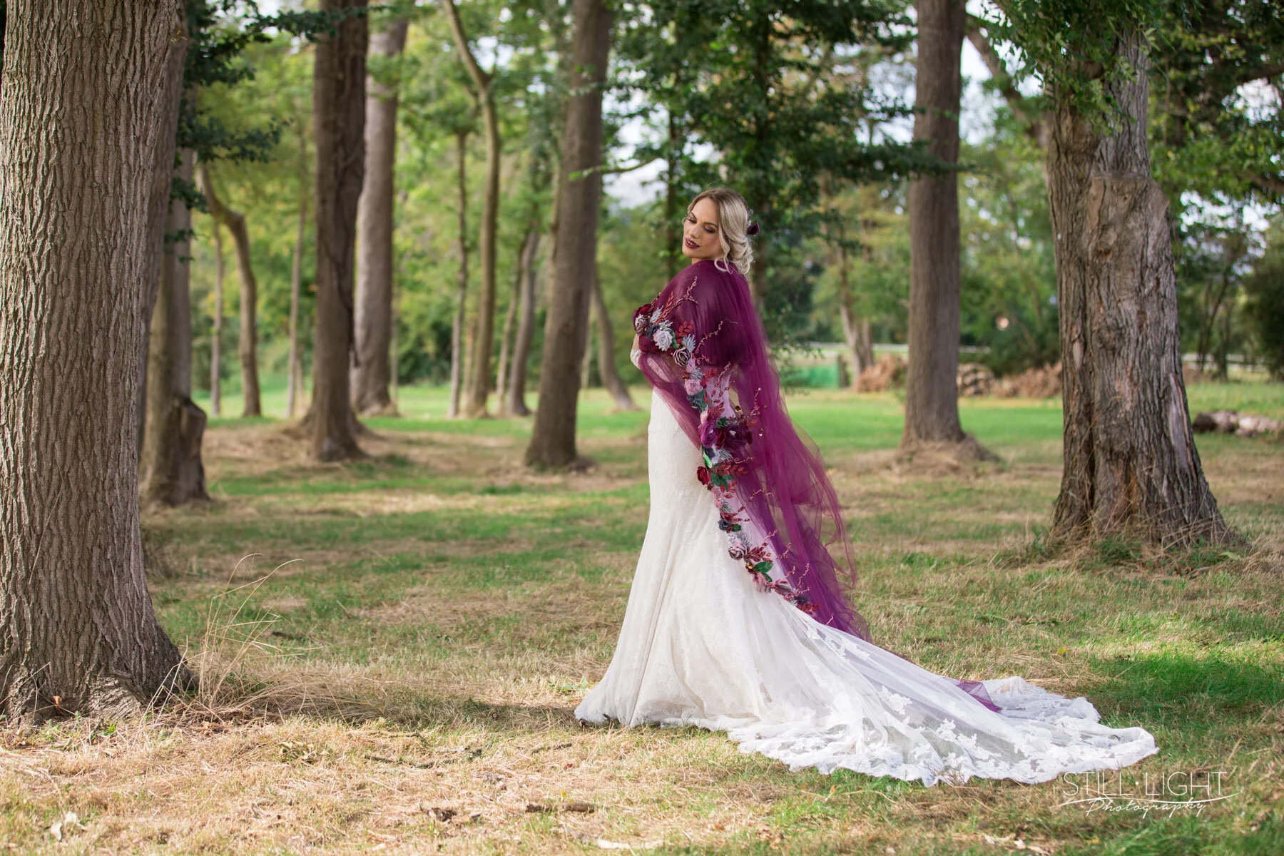 Editoral bride shot, standing amongst trees with a deep purple and floral embodied shawl