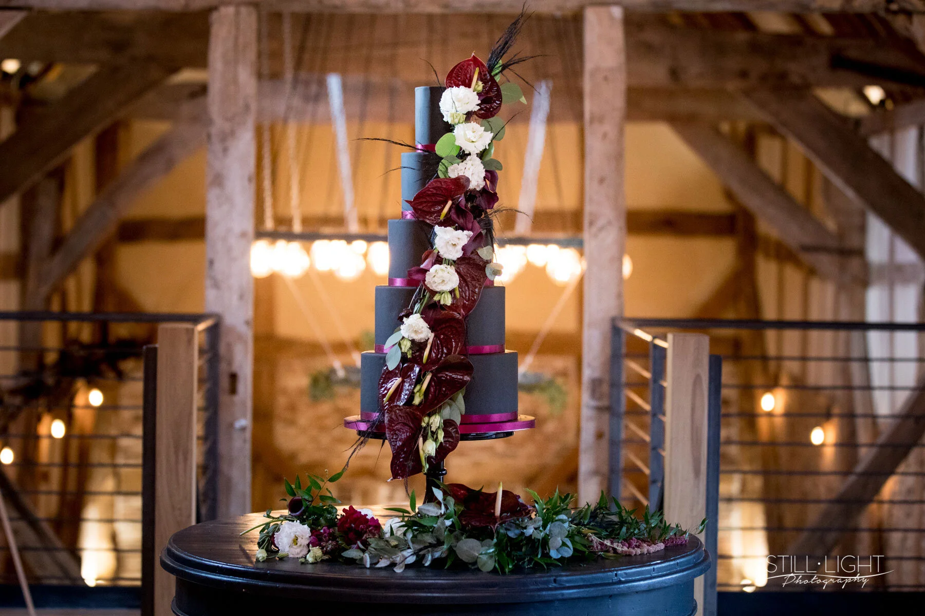Contemporary black iced wedding cake decorated with fresh white flowers and delicate foliage