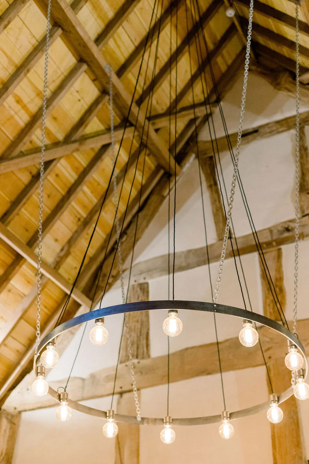 Circular steel chandelier hung from the eves of the barn