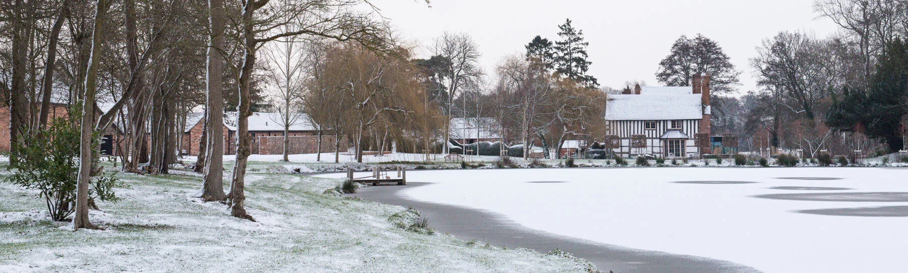 Wide shot of the grounds, barns, lake and house covered in snow