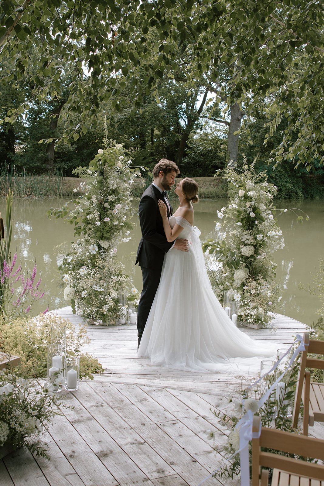 Bride and groom walking through the landscaped grounds surrounded by soft summer florals