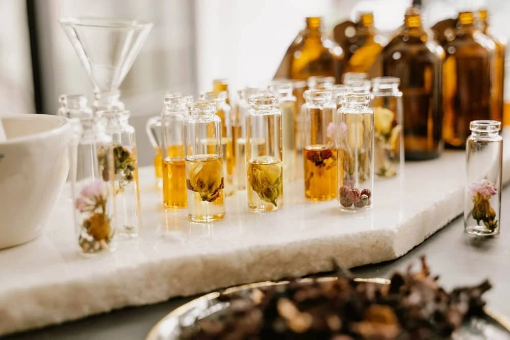 Orange coloured perfumes and flowers in small glass bottles and vials