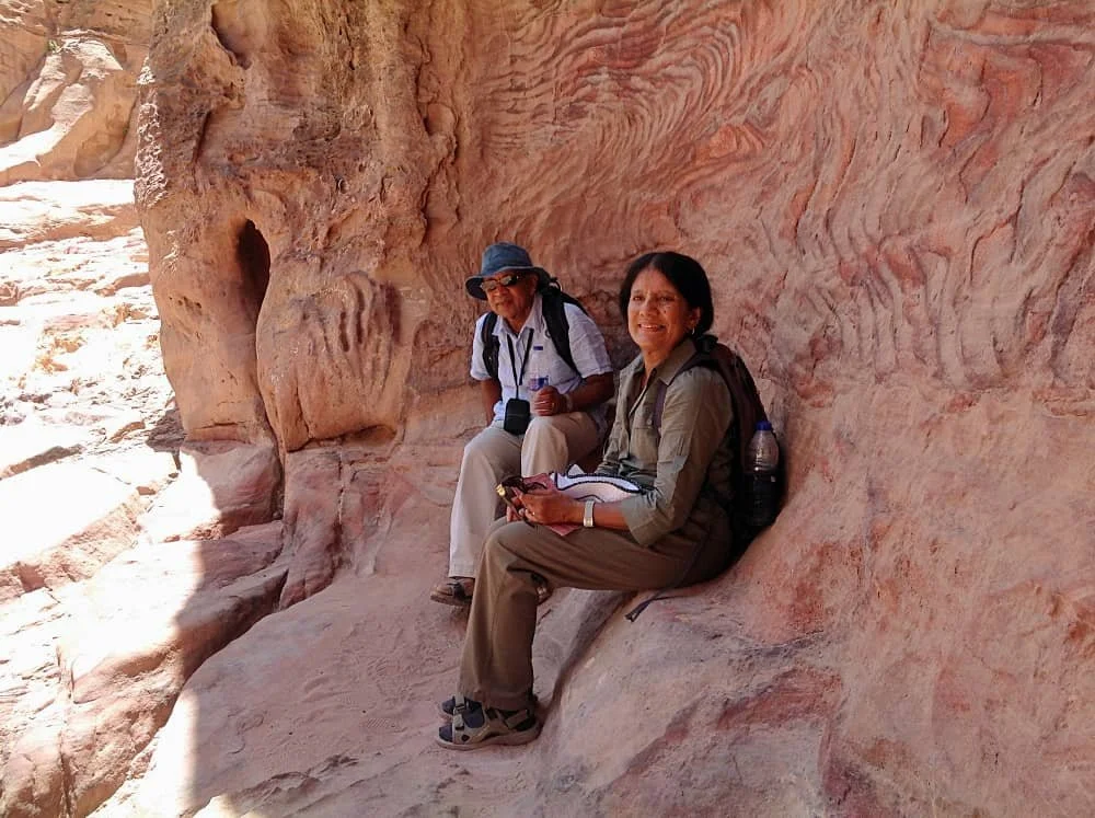 Sasha's parents sit down to rest on a rocky ledge while walking in Petra, Jordan