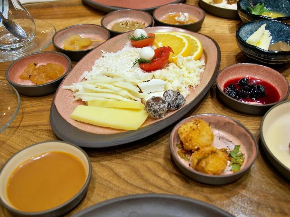 Close up of a cheese plate, surrounded by smaller dishes filled with jams, butter and spreads and Limon Kahvalti in Galata