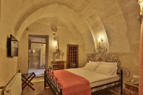 A comfortable bed in a cave room with high arched ceilings at Jacob's cave suites, cappadocia hotel with private balcony