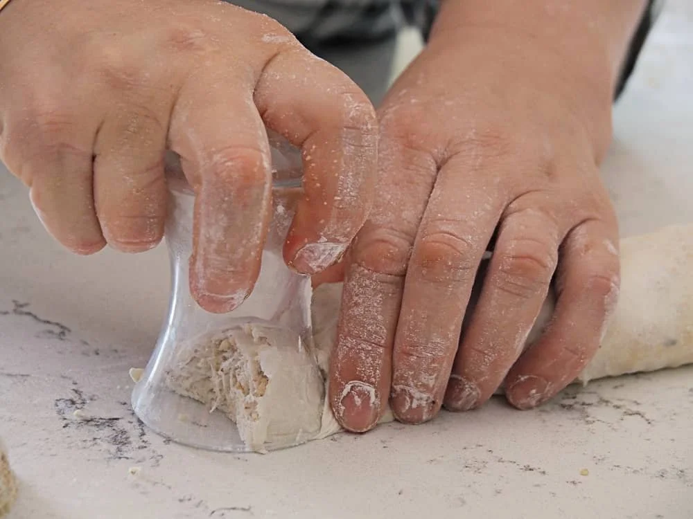 Close up of hands cutting baklava pastry with a tea glass