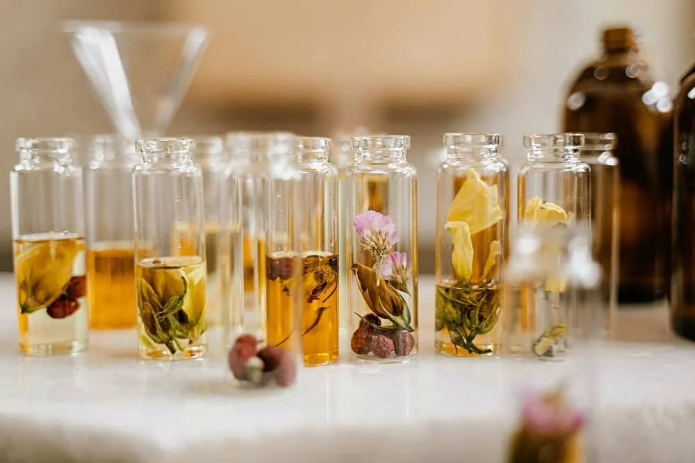Close up of orange and yellow coloured liquids and flowers in small glass vials