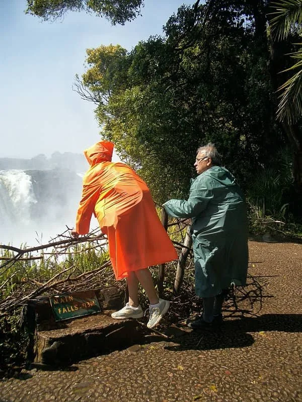 Sasha's mum leaning over the edge of the fence to look closer at the Victoria Falls from the Zimbabwean side