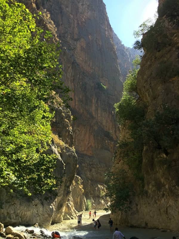 14 day travel itinerary turkey People in the distance wading through water and surrounded by huge cliff walls in Saklıkent Gorge in TĂŒrkiye