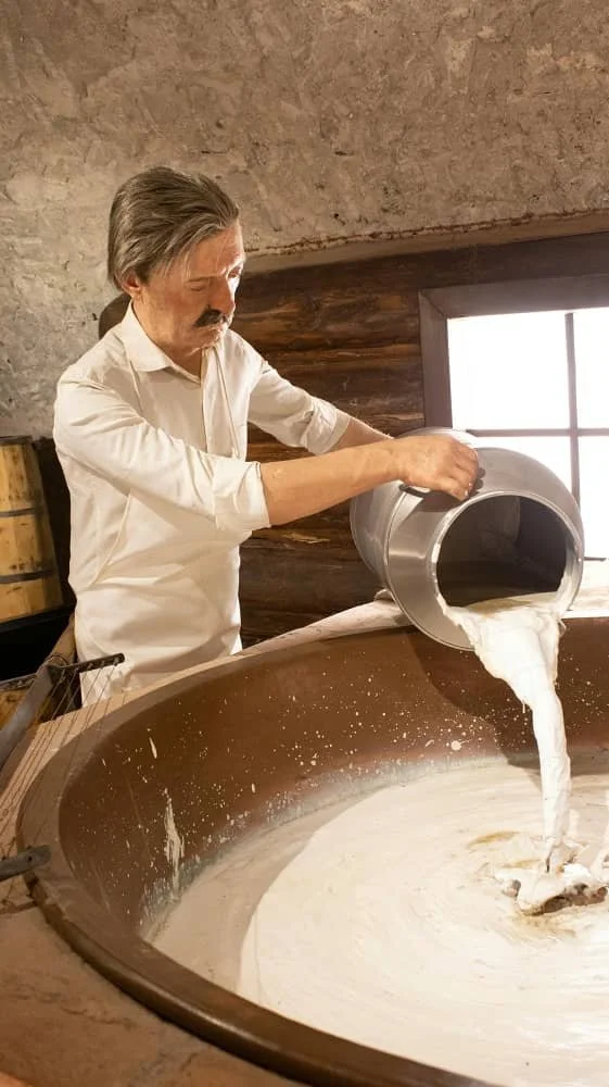 A diorama at the Kars Cheese Museum showing a full-size model of a man pouring milk into a large vat during the cheese making process