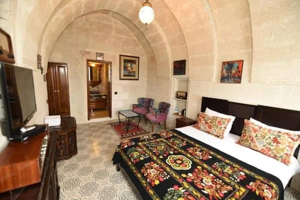 A double bed with an ornate bedspread in a room with arched ceilings at Canela Cave Hotel, best luxury hotels in cappadocia turkey