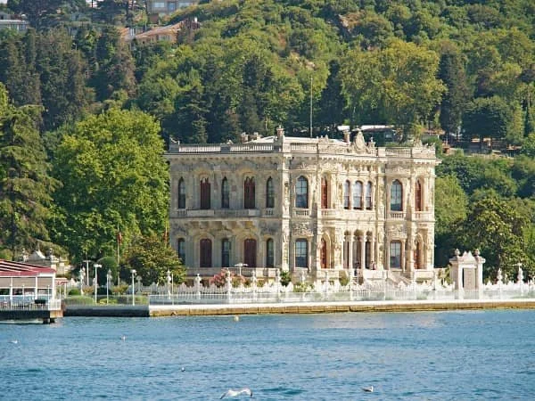 Palace surrounded by trees at the water's edge as seen from a Bosphorus tour