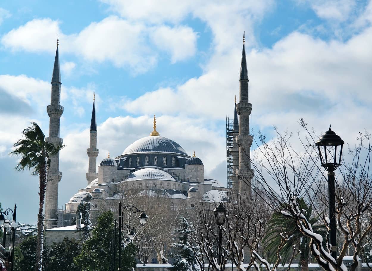 The domes of the Blue Mosque dusted with snow in January 2022 with a cloudy blue sky in the background, winter in istanbul weather