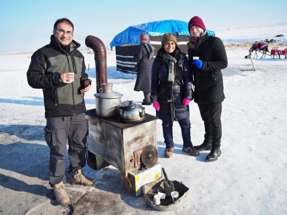 Sasha and Vincent stand on the ice having a cup of tea from a stove set up on the ice on Lake Cildir in Kars Turkey