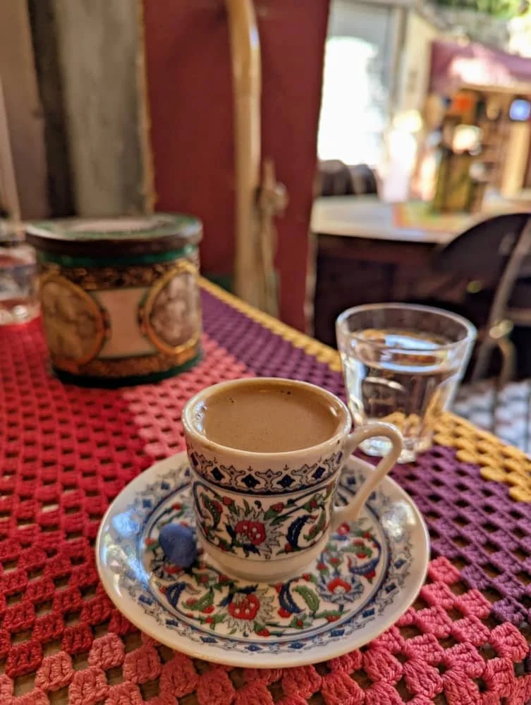 Close up of a Mardin-style Turkish coffee in a brightly coloured cup and saucer on a crochet table cloth at Cafe Naftalin in Balat in Istanbul